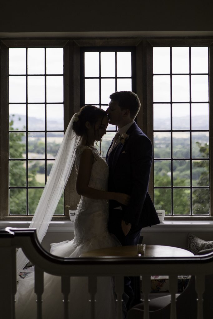 Bride and groom in front of window. Silhouette of bride and groom kissing.